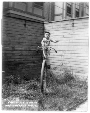 Baby_on_large_unicycle_held_up_by_ropes